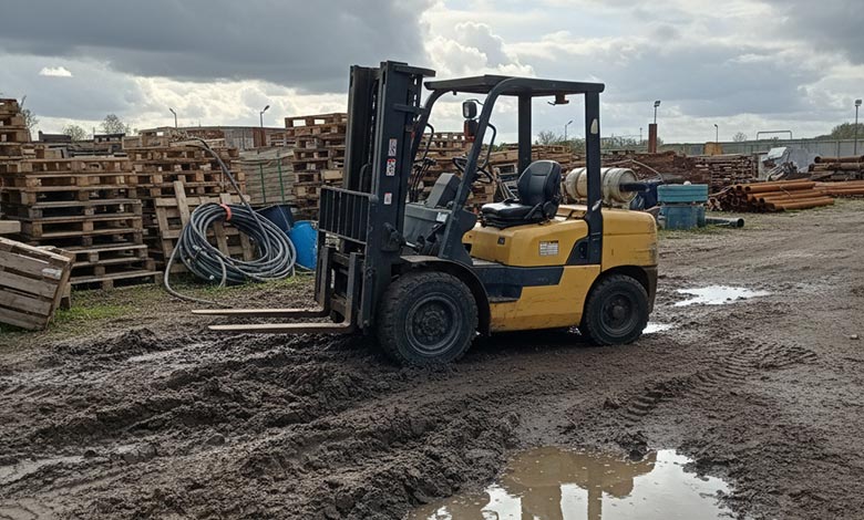 A close-up of a standard forklift's wheel spinning in the mud