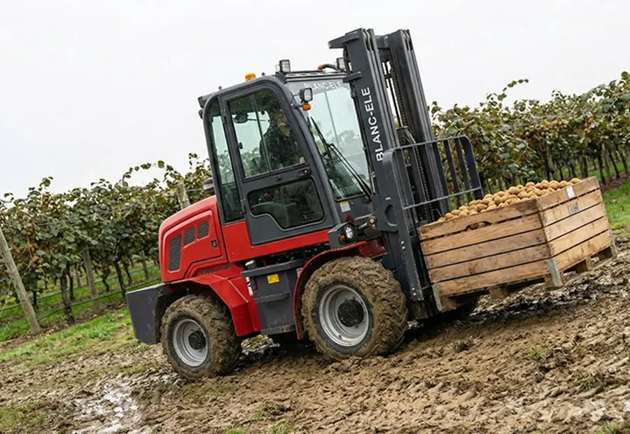 Rough terrain forklift carrying a load through muddy outdoor ground for FWD RWD and 4WD drive type comparison