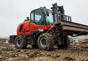 Rough terrain forklift working on a muddy construction site during rainy season